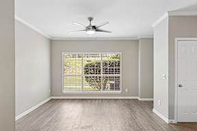 A room with a ceiling fan and a window with blinds.