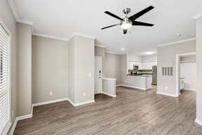 A room with a ceiling fan and wooden flooring.