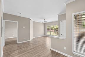 A room with a ceiling fan and sliding glass doors.