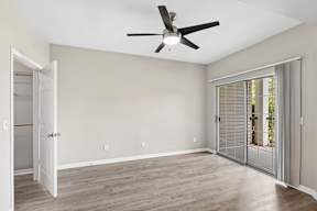 A room with a ceiling fan and sliding glass doors.