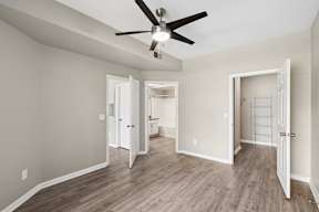A room with a ceiling fan and light fixture, and a wooden floor.