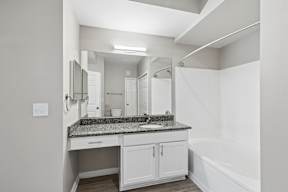 A white bathroom with a sink and mirror.