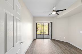 A room with a ceiling fan and a door leading to a balcony.