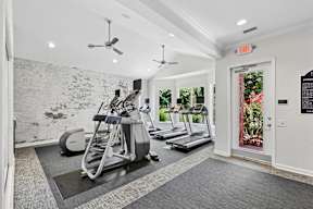 A gym with treadmills, elliptical machines and a fan.