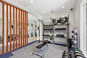 A gym with a variety of equipment including TRX, kettlebells, and a bench.
