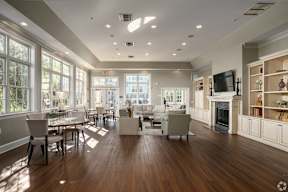 A large, well-lit living room with wooden floors and furniture.