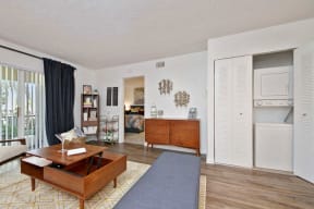 Furnished living room with open closet door showing stack-able washer and dryer