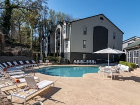 a swimming pool with chairs and umbrellas in front of a building