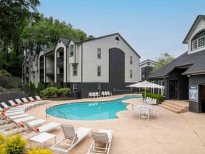 a swimming pool with chairs around it in front of a building