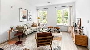 A living room with a couch, chair, and a table with a plant on it.