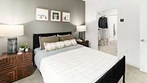 A bedroom with a large bed and a wooden dresser.