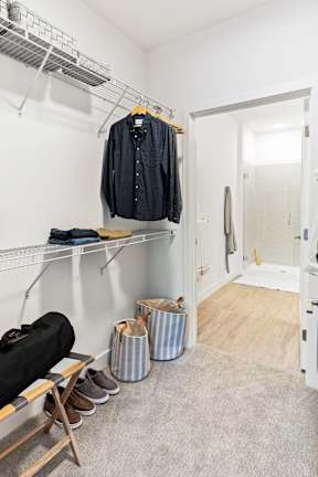 A room with a coat hanging on a rack and a pair of shoes on the floor.