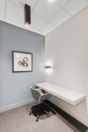 A room with a grey wall and a framed picture hanging on it.