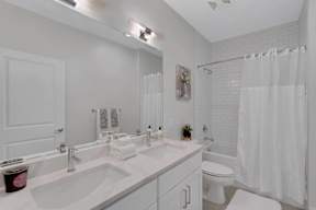 A white bathroom with a double sink and a toilet.