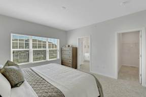 A bedroom with a large bed and a window with blinds.