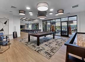 A modern living room with a pool table and a view of the outdoors.