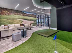 A room with a golf putting green and a large picture of a golf course on the wall.