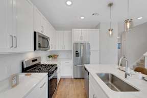 A modern kitchen with white cabinets and stainless steel appliances.