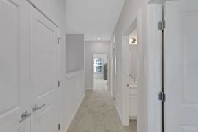 A long hallway with white doors and carpeting.