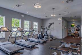 Fitness center at Pennbrook Station Apartments in Lansdale, PA, featuring exercise machines and large windows.