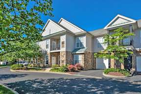 Exterior view of Pennbrook Station Apartments in Lansdale, PA, featuring landscaped gardens and units with balconies.