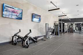 A gym with exercise equipment and a TV on the wall.