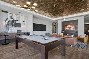 A pool table is in the middle of a room with a fireplace and a couch.