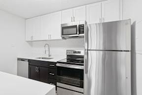 A modern kitchen with a stainless steel refrigerator, microwave, oven, and sink.