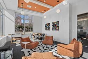 A modern living room with orange chairs and a black and white floor.