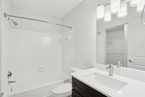A white bathroom with a toilet, sink, and shower.