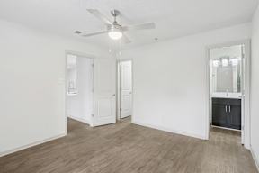 A room with a ceiling fan and wooden flooring.