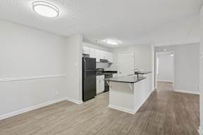 A kitchen with a black refrigerator and white cabinets.
