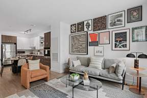 A living room with a grey couch, a coffee table, and a wall with framed pictures.