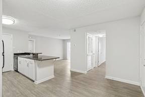 A kitchen with white cabinets and a black countertop.