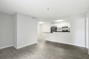 A spacious room with a kitchenette and wood flooring.