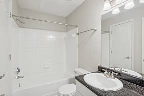A white bathroom with a toilet, sink, and shower.