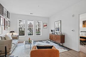 A living room with a couch, a chair, a coffee table, and a large window.