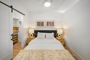 A bedroom with a bed, nightstands, and a painting on the wall.