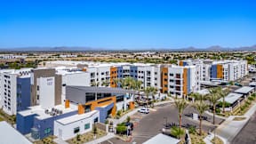 A modern building complex with a parking lot in front.