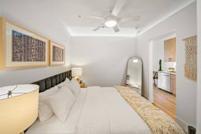A bedroom with a bed, a ceiling fan, and a mirror.