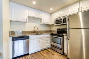 Dishwasher, refrigerator, stainless steel appliances and wood floors in the kitchen
