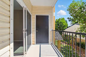 A balcony with a black door and a metal railing.