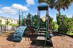 A playground with a green slide and a brown wooden platform.