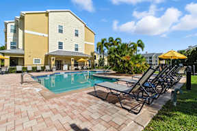 A large yellow building with a pool in front.