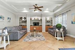 A living room with a grey couch, a white coffee table, and a ceiling fan.