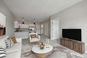 A modern living room with a white sofa, a coffee table, and a flat-screen TV. at The Hendrickson, Falcon Heights, Minnesota