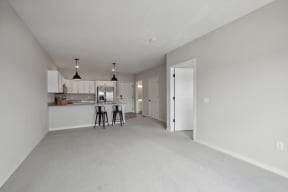 the living room and kitchen of an apartment with white cabinets and a white kitchen counter at The Hendrickson, Falcon Heights, MN, 55113