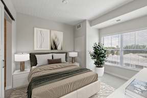 A bedroom with a large bed and a potted plant. at The Hendrickson, Falcon Heights, MN