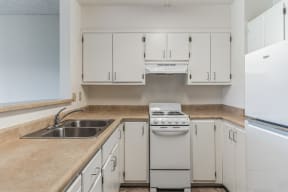 an empty kitchen with white cabinets and appliances and a sink