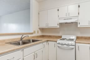 an empty kitchen with white cabinets and a stove and sink